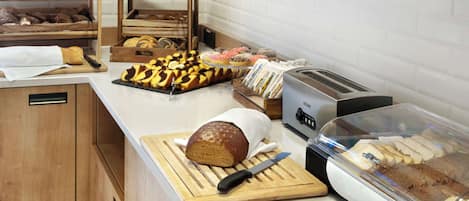 Eine Bäckereitheke mit verschiedenen Backwaren, einem Brotlaib, einem Toaster und einer Brotdose.