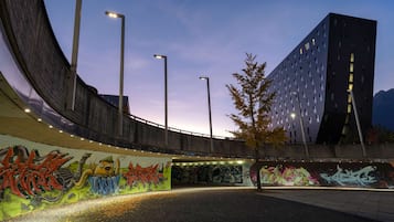 A curved building with graffiti, streetlights, and a modern building in the background.