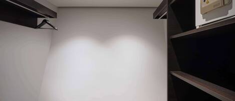 Una habitación con piso de madera, pared blanca e iluminación empotrada en el techo. Hay un panel de control en la pared.