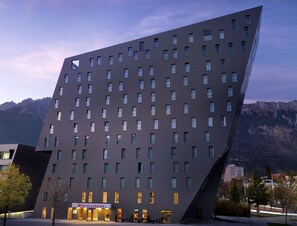 Un hotel moderno con un diseño angular distintivo, con varios pisos y una entrada destacada.