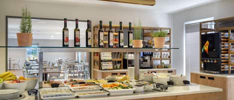 A buffet area with various food items, wine bottles, and potted plants.