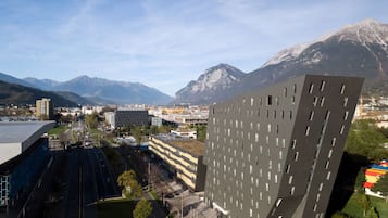 En moderne bygning med et unikt vinklet design, omgivet af en by og bjerge i baggrunden.