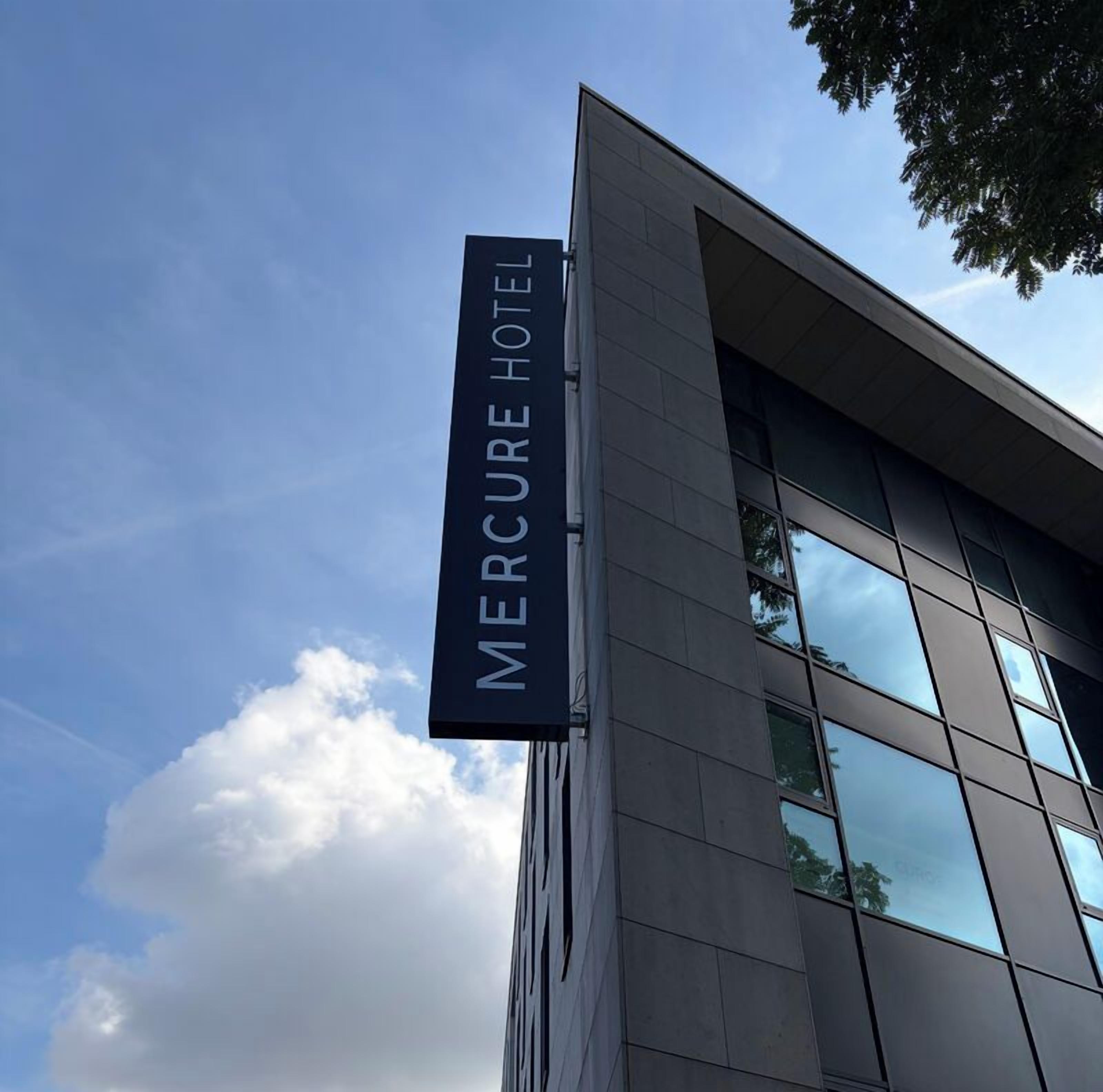 Ein Hotel-Schild mit der Aufschrift 'Mercure Hotel' vor blauem Himmel.