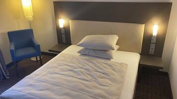 A hotel room with a bed, two bedside lamps, a chair, and a wall-mounted light fixture.