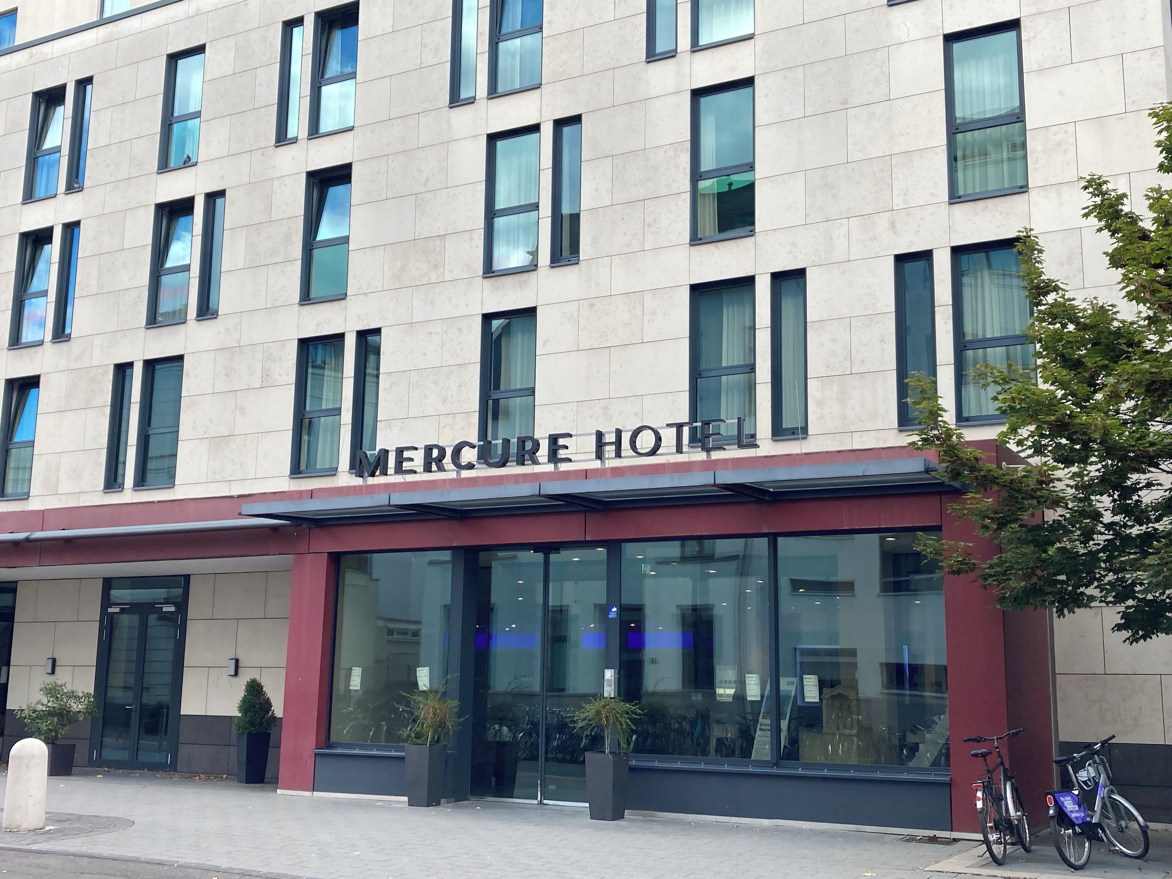 A hotel with a modern facade, large windows, and a sign reading 'Mercure Hotel'.
