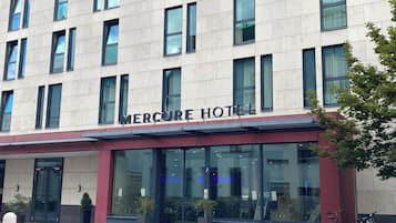 A hotel with a modern facade, large windows, and a sign reading 'Mercure Hotel'.