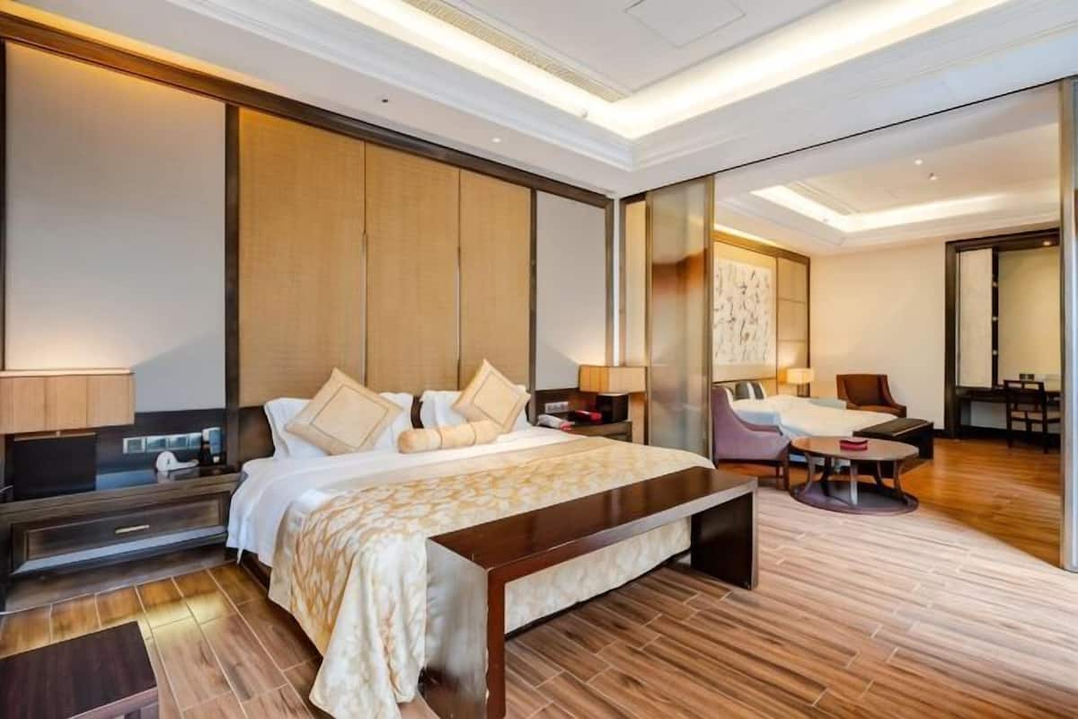 Una habitación de hotel moderna con una cama grande, mesitas de noche, un escritorio, una silla y vistas al pasillo.