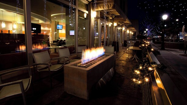 Un espacio al aire libre con asientos, una chimenea y vistas al interior del restaurante.