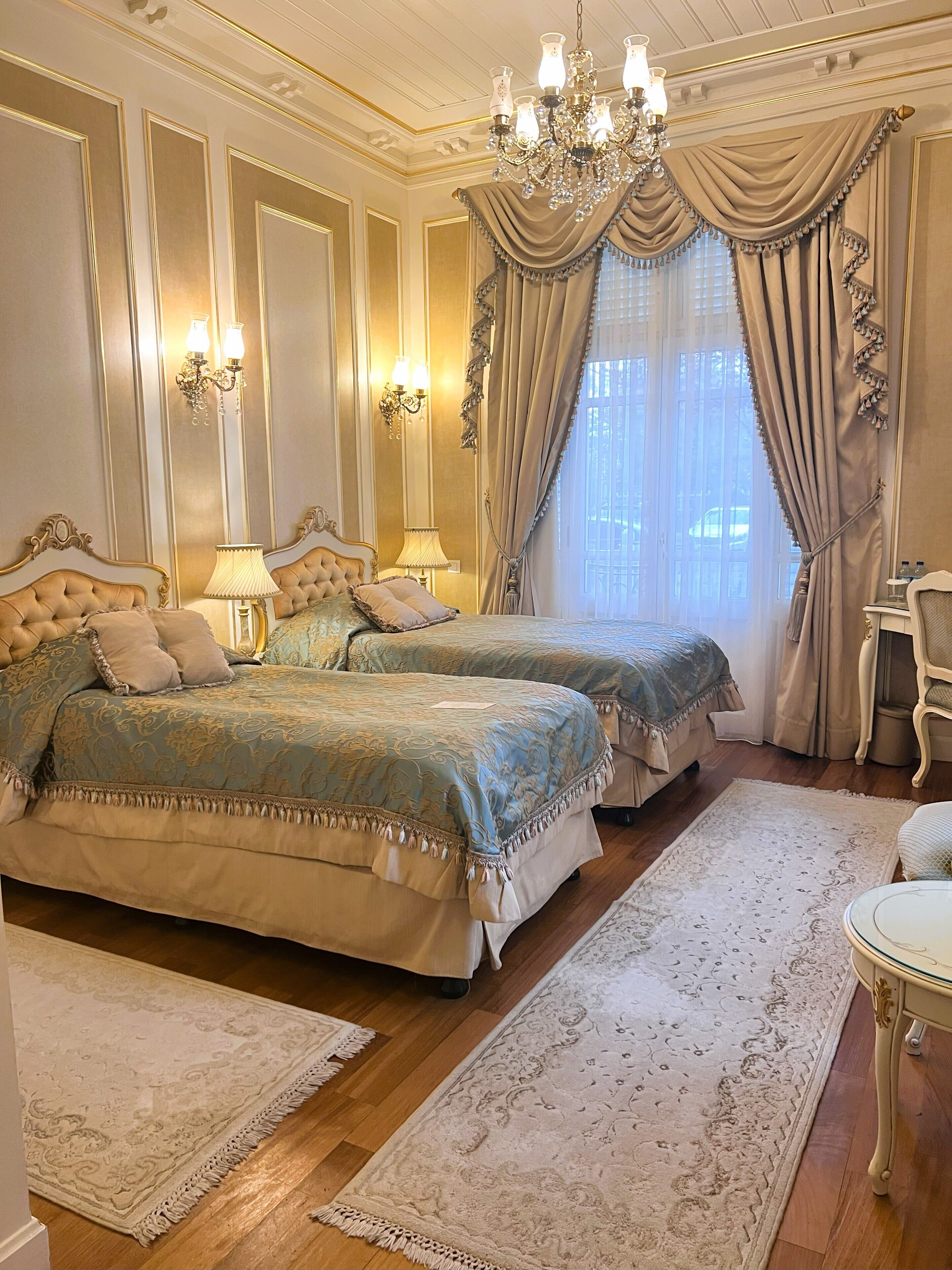 Un dormitorio lujoso con dos camas grandes, candelabros ornamentales y decoración clásica.