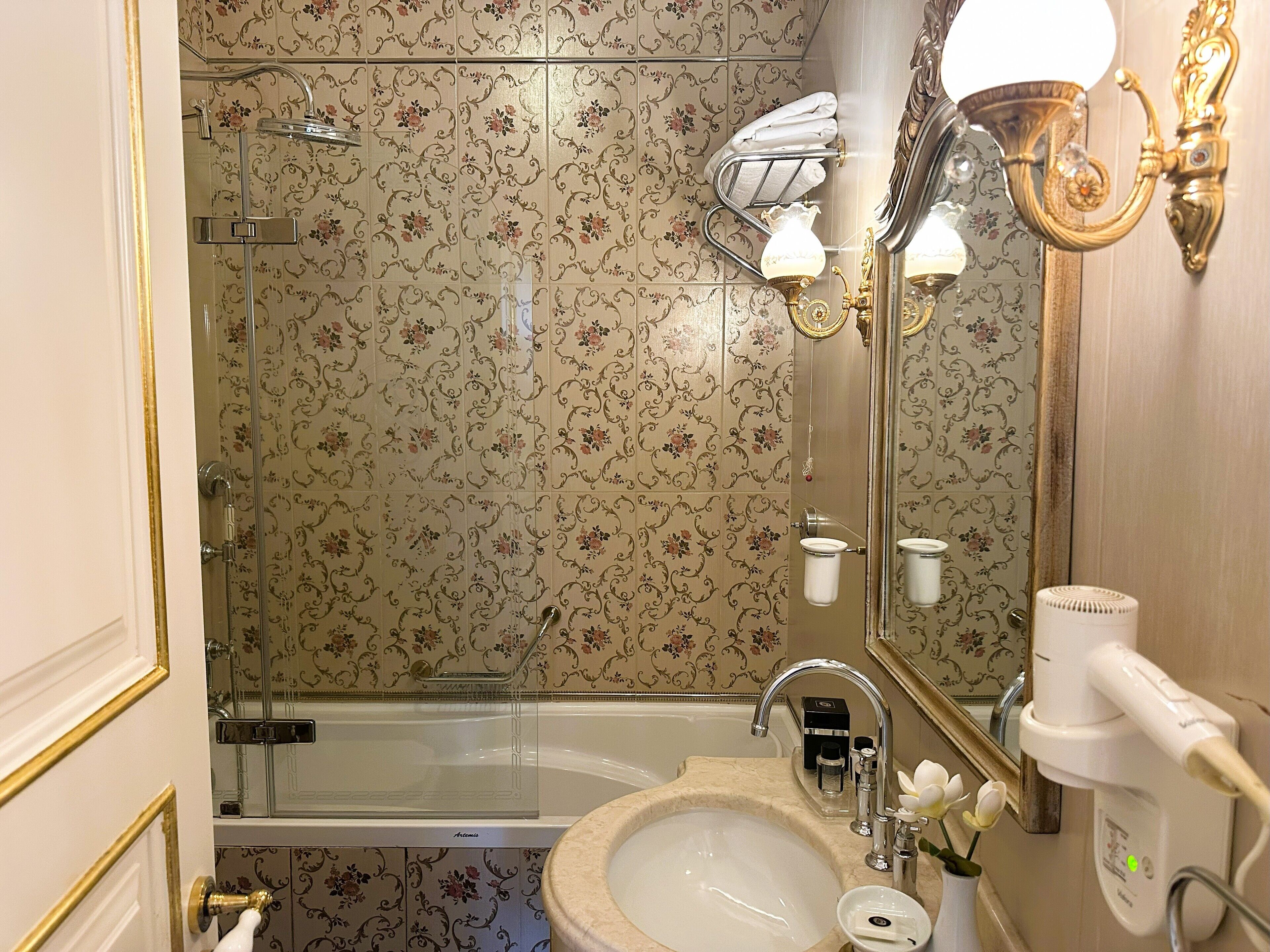 Un baño con bañera, lavamanos, espejo y secador de pelo.