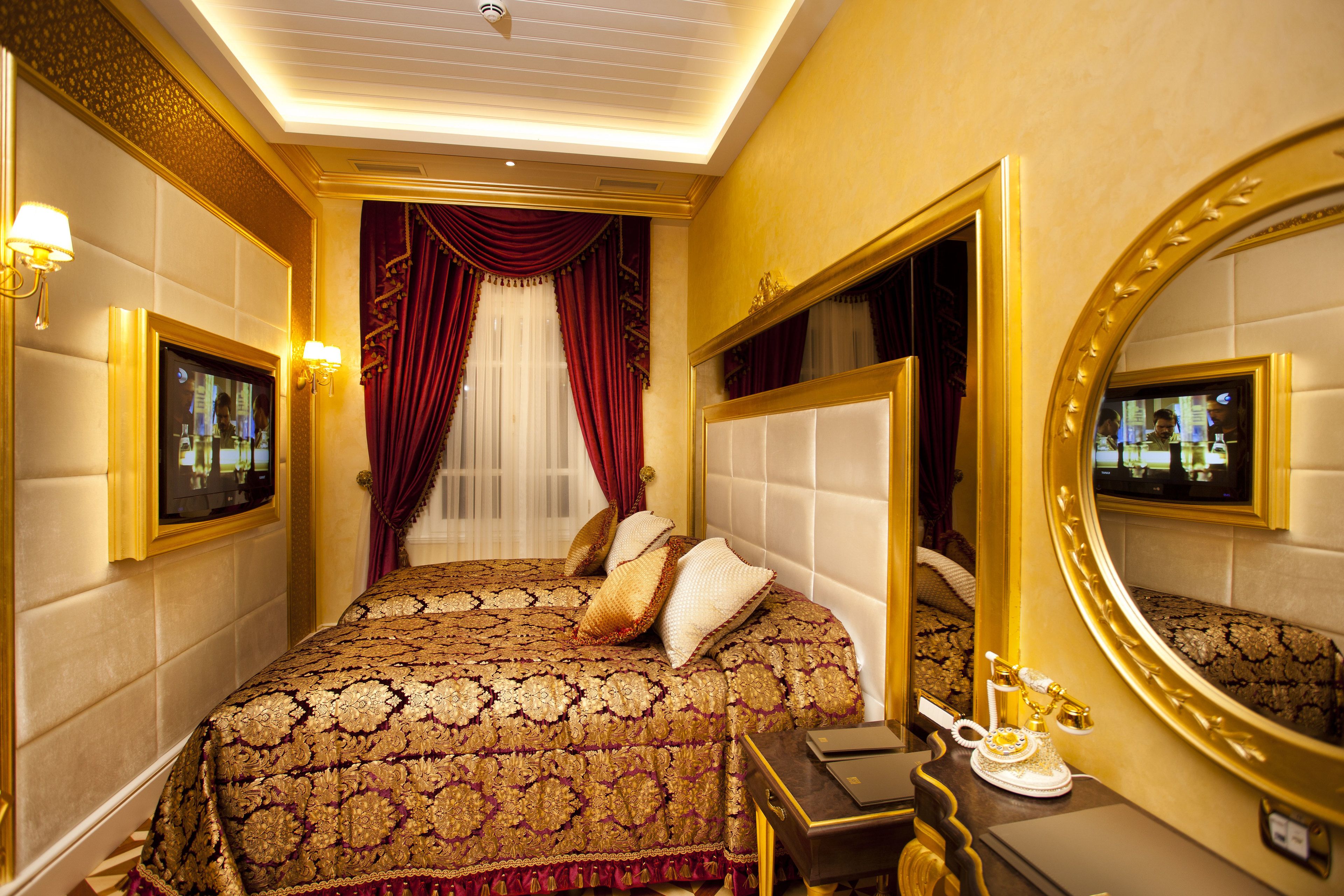 A luxurious hotel room with a large bed, a vanity with a mirror, and a television on the wall.