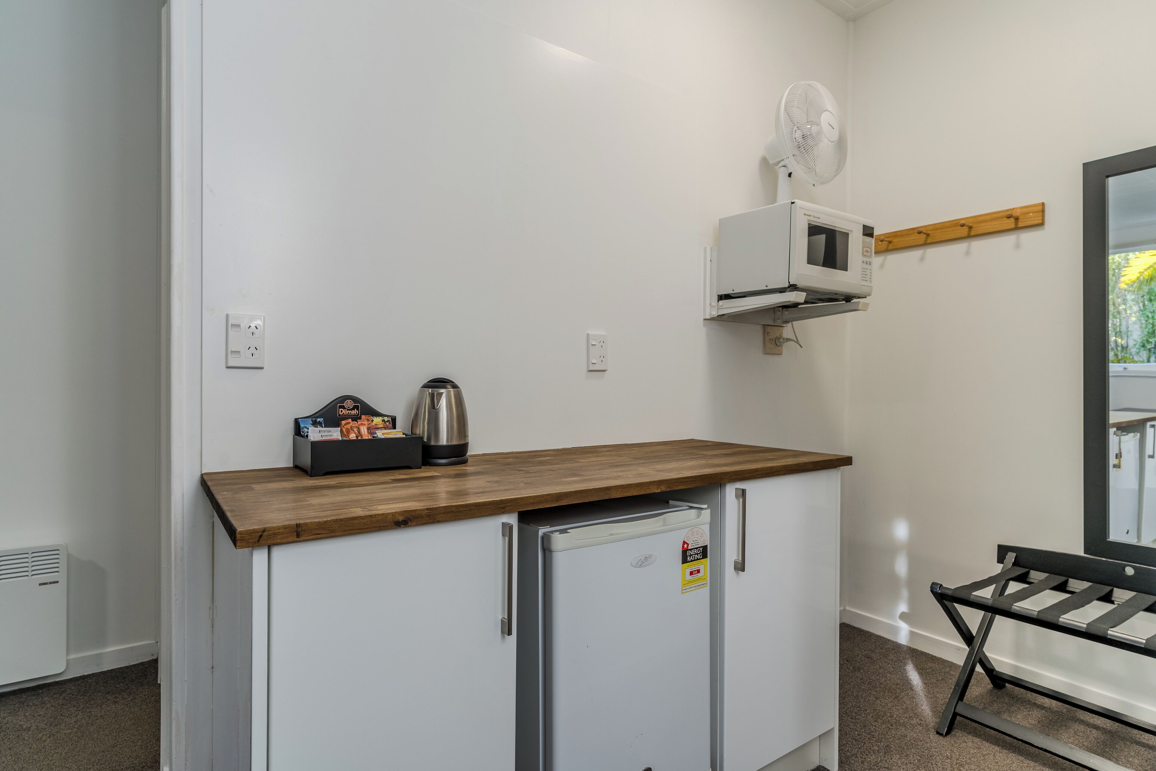 A kitchenette with a microwave, kettle, and a small refrigerator.