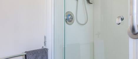 A glass-enclosed shower area with a towel rack and a showerhead.
