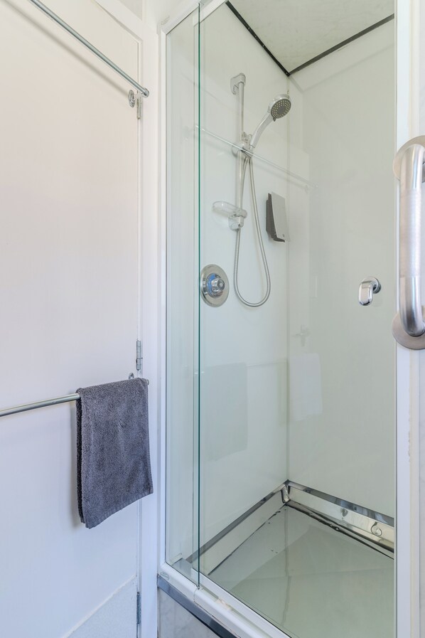 A glass-enclosed shower area with a towel rack and a showerhead.