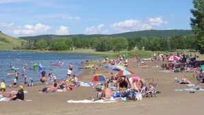 Una spiaggia affollata con persone che nuotano e si prendono il sole, tende e ombrelloni.