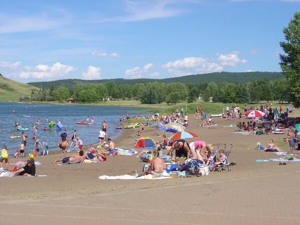 Una playa concurrida con gente nadando y tomando el sol, tiendas de campaña y sombrillas.