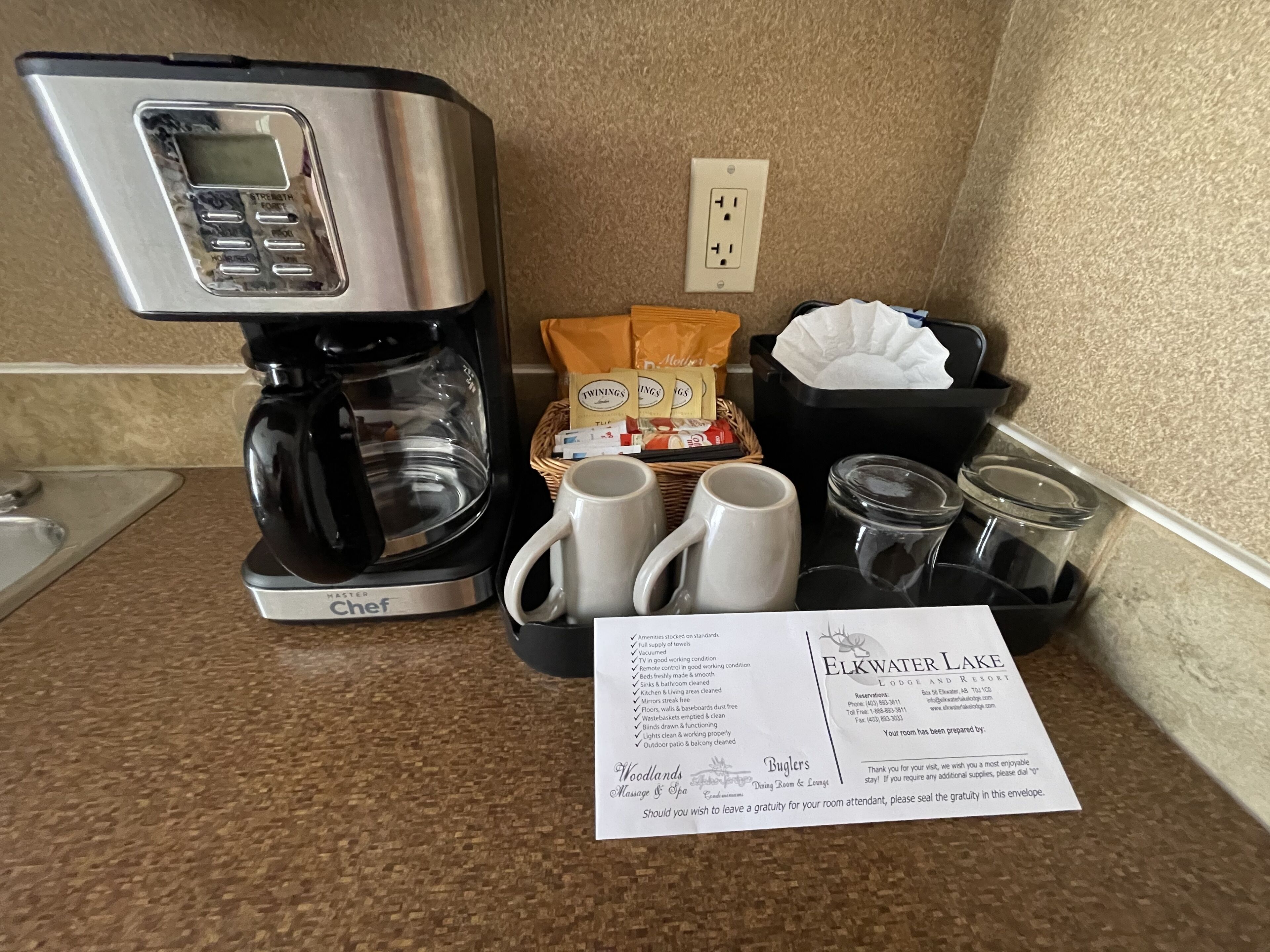 Una cocina con cafetera, tazas, una cesta de aperitivos y una tarjeta de bienvenida del Elkwater Lake Lodge & Resort.