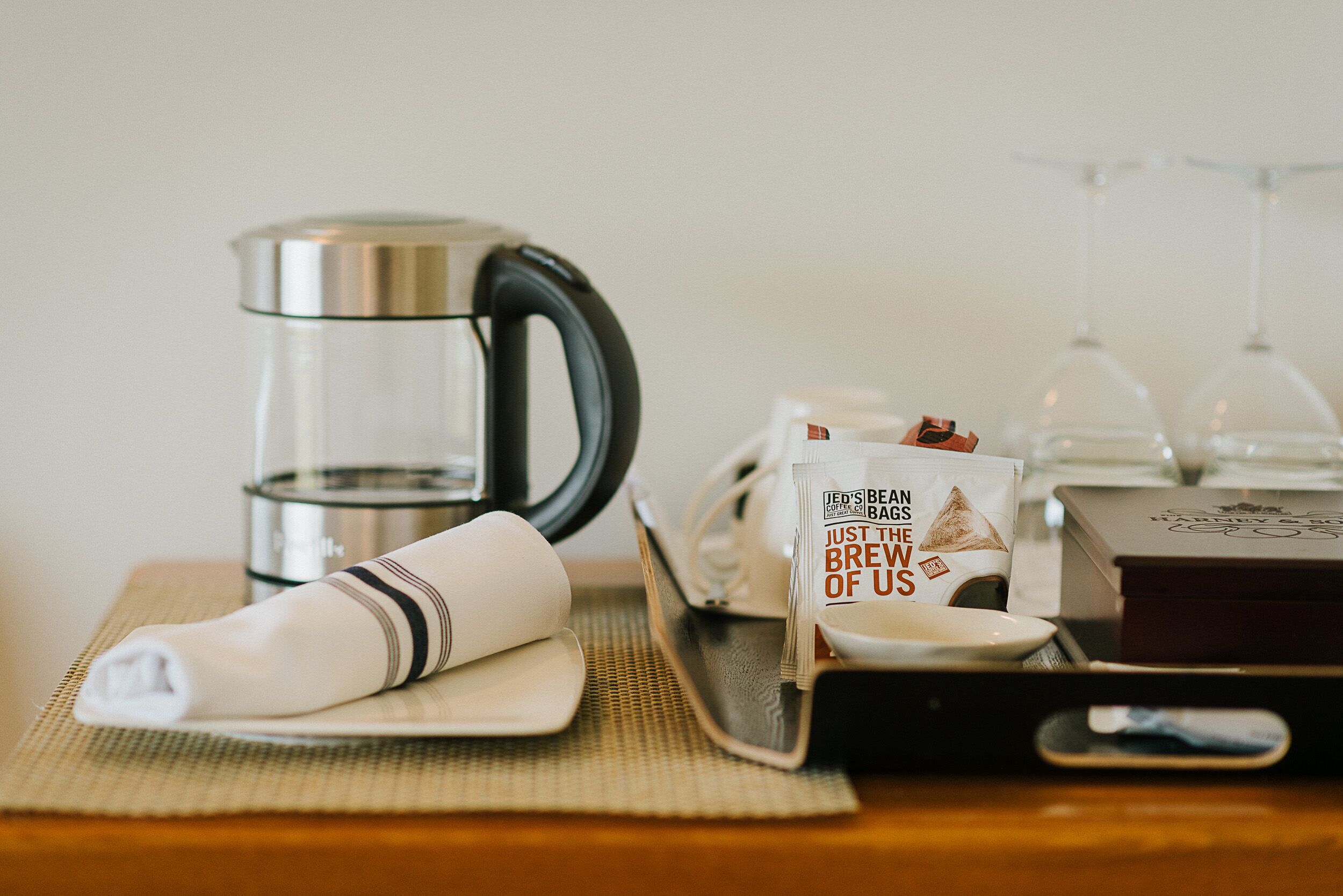 A coffee maker, a coffee bag, a glass of water, and a wine glass on a table.