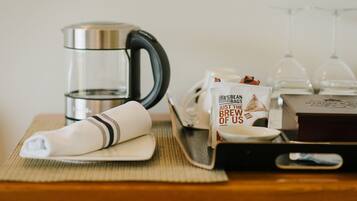 A coffee maker, a coffee bag, a glass of water, and a wine glass on a table.