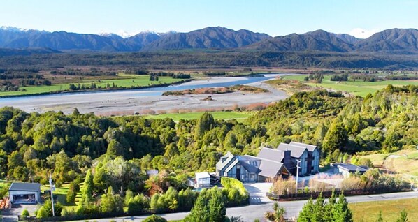 A modern house with a large driveway and a river in the background.