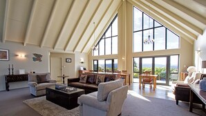A spacious living room with high ceilings, large windows, and a view of the outdoors.