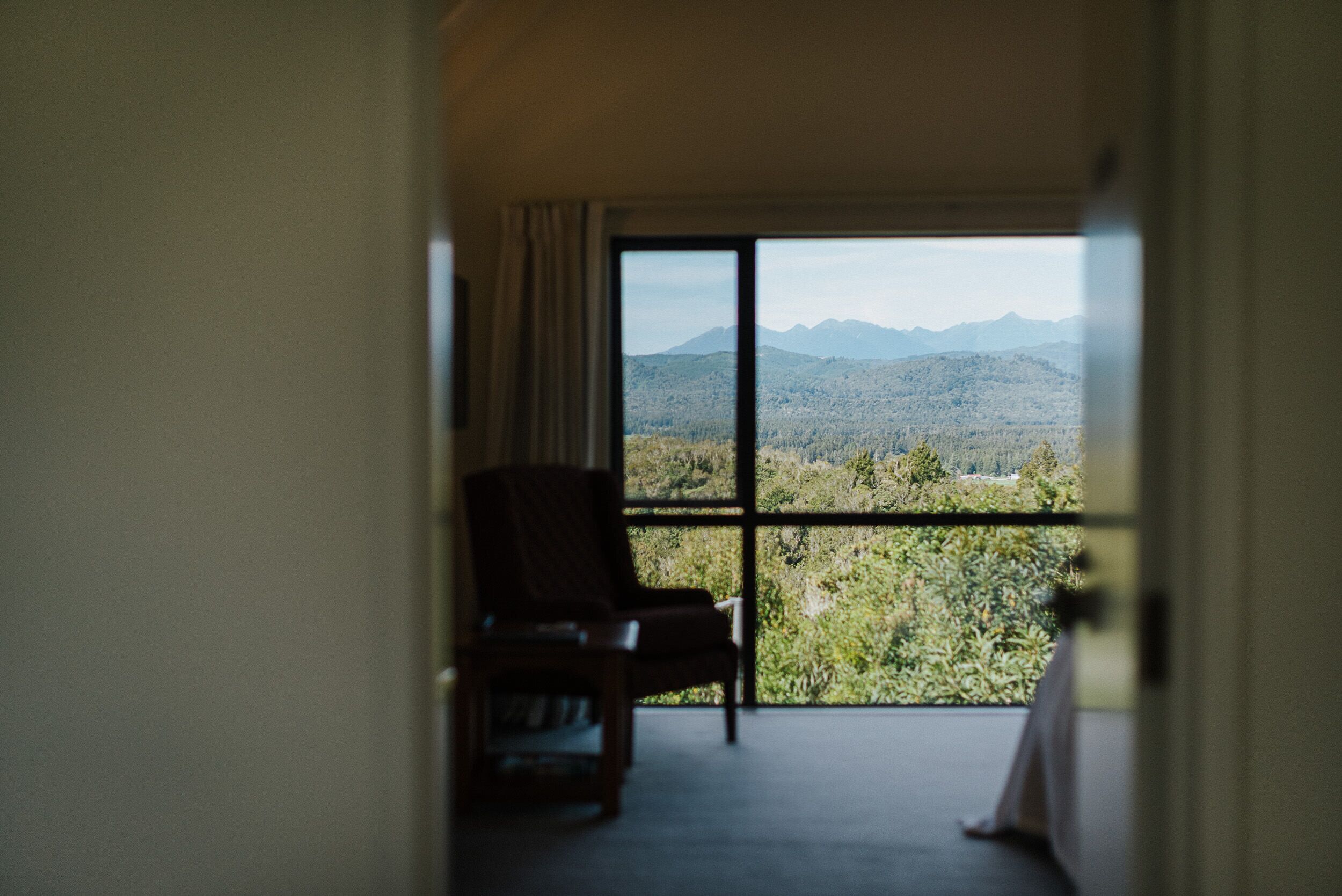 Una habitación con un gran ventanal corredera que da a un balcón con vistas a la montaña.