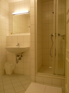 A bathroom with a sink, mirror, and shower.
