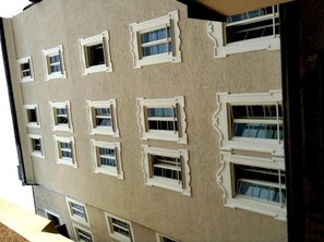 A building facade with multiple windows, some with open shutters.