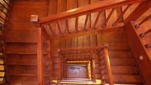 Una escalera de madera con barandilla y vista al piso inferior.