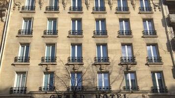 Un immeuble à plusieurs étages, avec une enseigne indiquant « Grand Hôtel » au niveau du rez-de-chaussée.