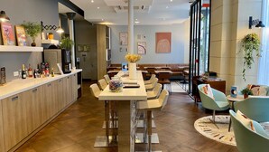 A modern dining area with a long table, chairs, and a bar counter. - Grand Hotel Clichy (Clichy)