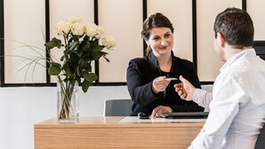 A professional setting with a wooden table, a vase of white flowers, and two individuals engaged in a discussion. - Grand Hotel Clichy (Clichy)