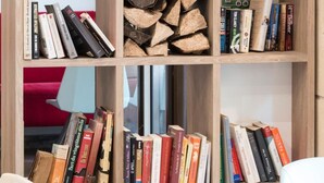 A bookshelf with books, a Buddha statue, and a potted orchid. - Grand Hotel Clichy (Clichy)