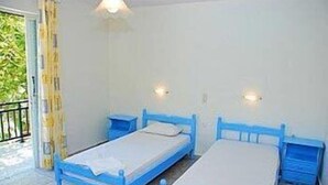 A small, simple room with two single beds, each with a matching nightstand. - Dimitra Hotel Apartments (Hersonissos)