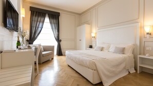 Hotelkamer met een groot bed, een bureau, een stoel, een televisie en een raam met gordijnen.