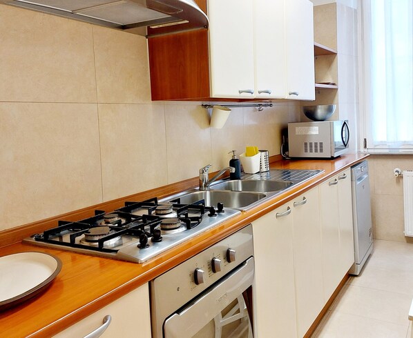 A kitchen with a gas stove, oven, microwave, and a sink. - Residenza Scipioni Luxury Rooms (Rome)