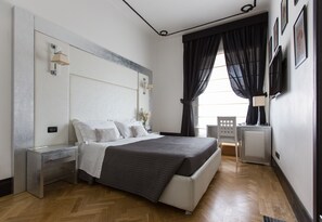 Een moderne slaapkamer met een groot bed, nachtkastjes, een stoel en een televisie.