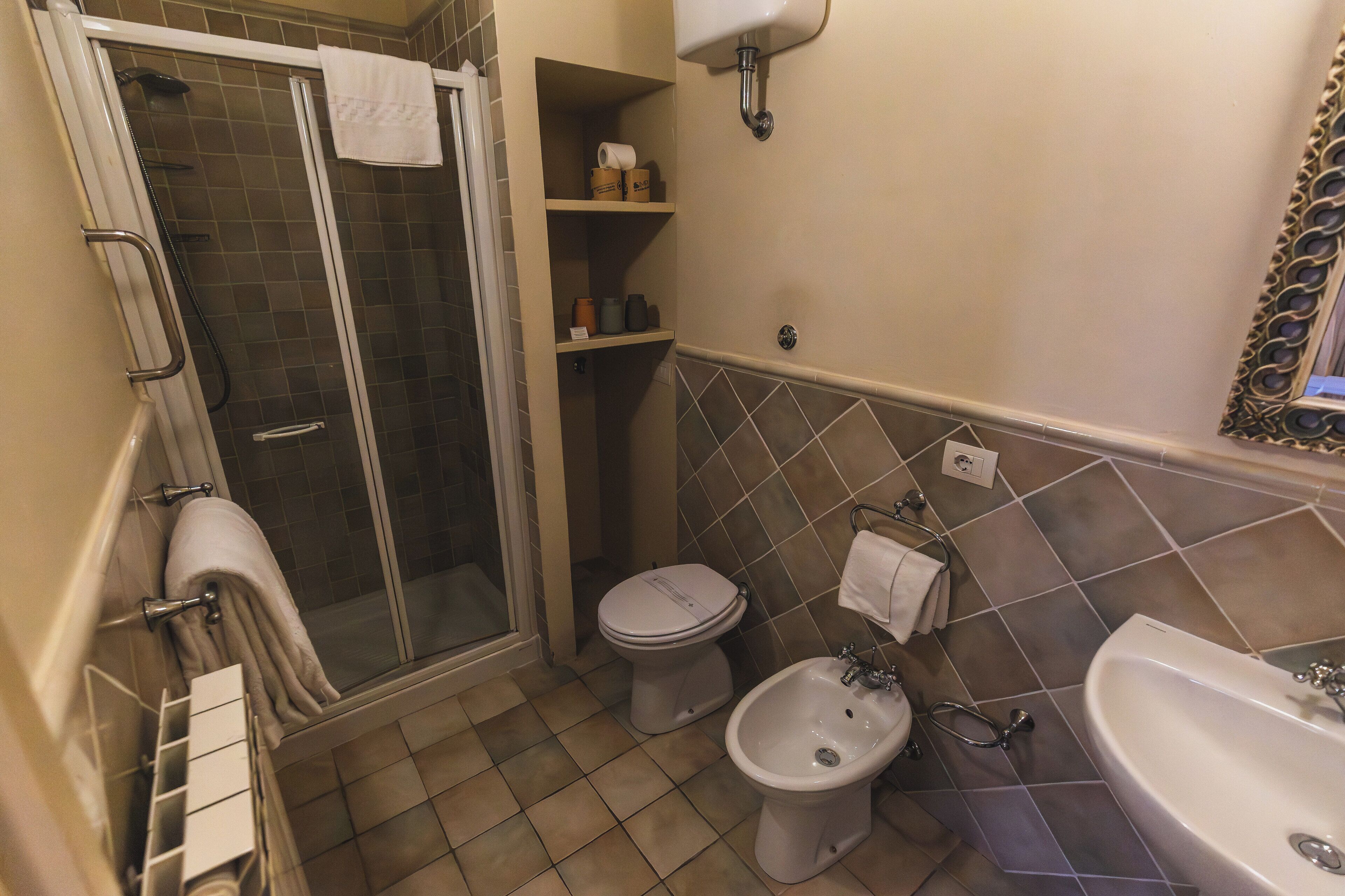 Un baño con ducha, inodoro, bidé y lavamanos.