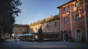 A courtyard with outdoor seating, a Christmas tree, and a building with arched windows and a tiled roof. - Borgo Di Colleoli Resort (Palaia)