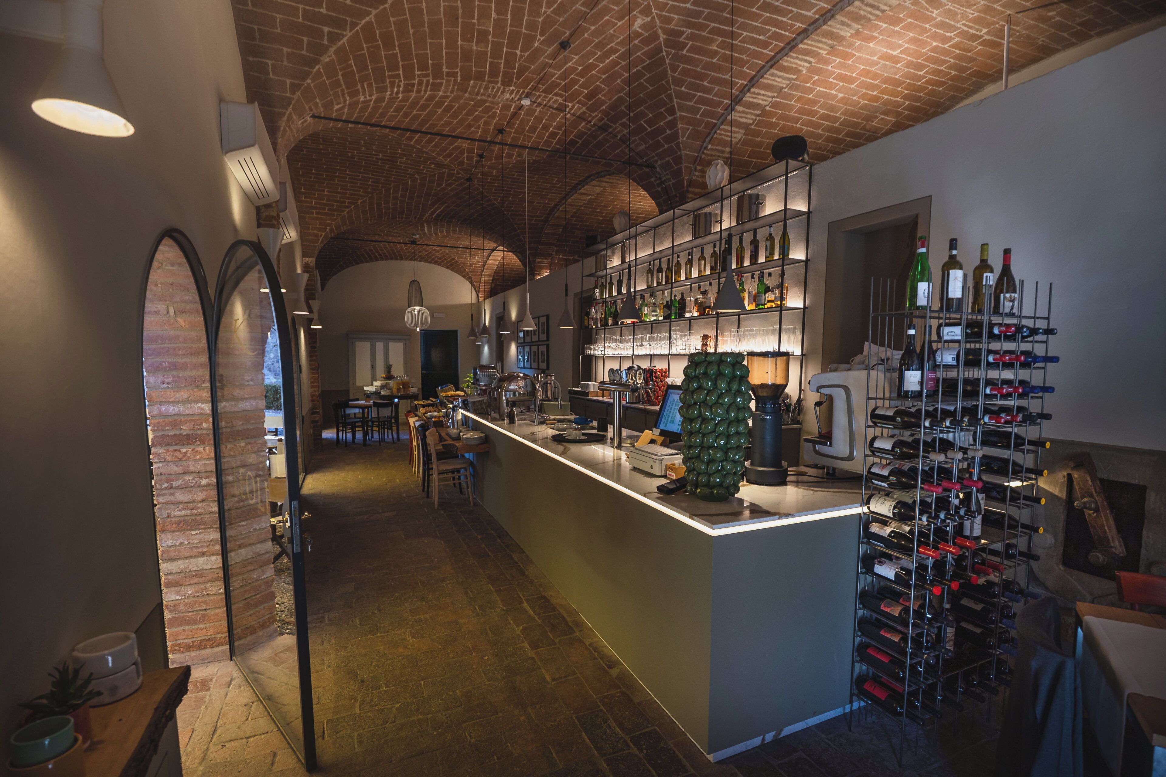 A bar area with a brick ceiling, a wine rack, and a counter with a computer.