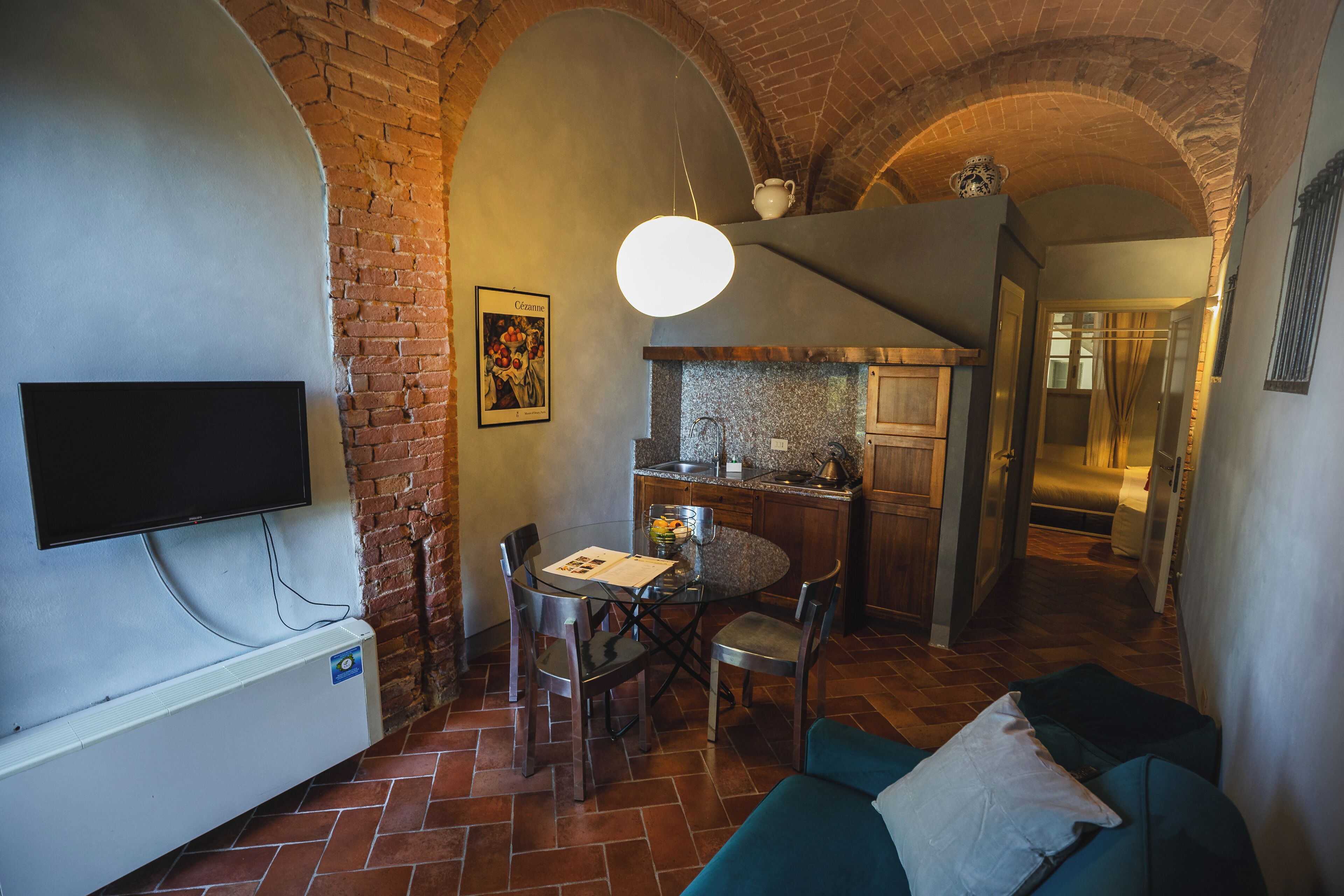 Un salon confortable avec un téléviseur, une table à manger avec des chaises, une cuisine avec un plan de travail et un escalier menant à un autre niveau.
