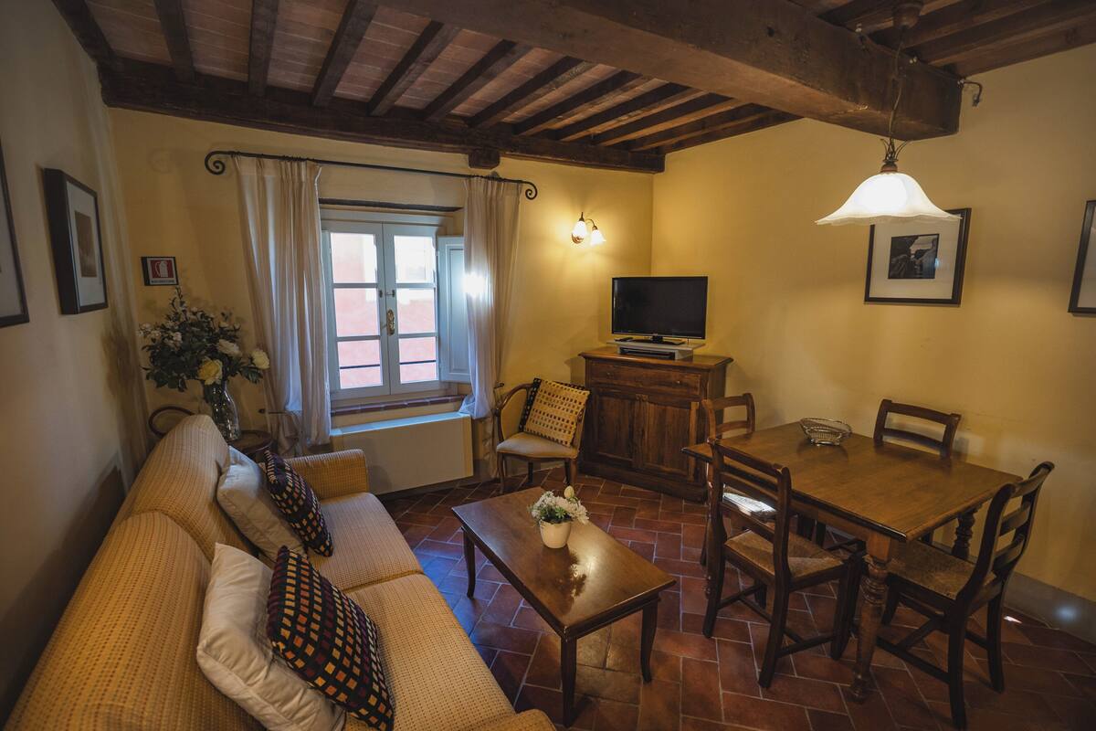 Una sala de estar acogedora con un sofá, una mesa de comedor de madera y un televisor.