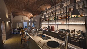 A bar area with a long counter, shelves with bottles, and a brick ceiling. - Borgo Di Colleoli Resort (Palaia)