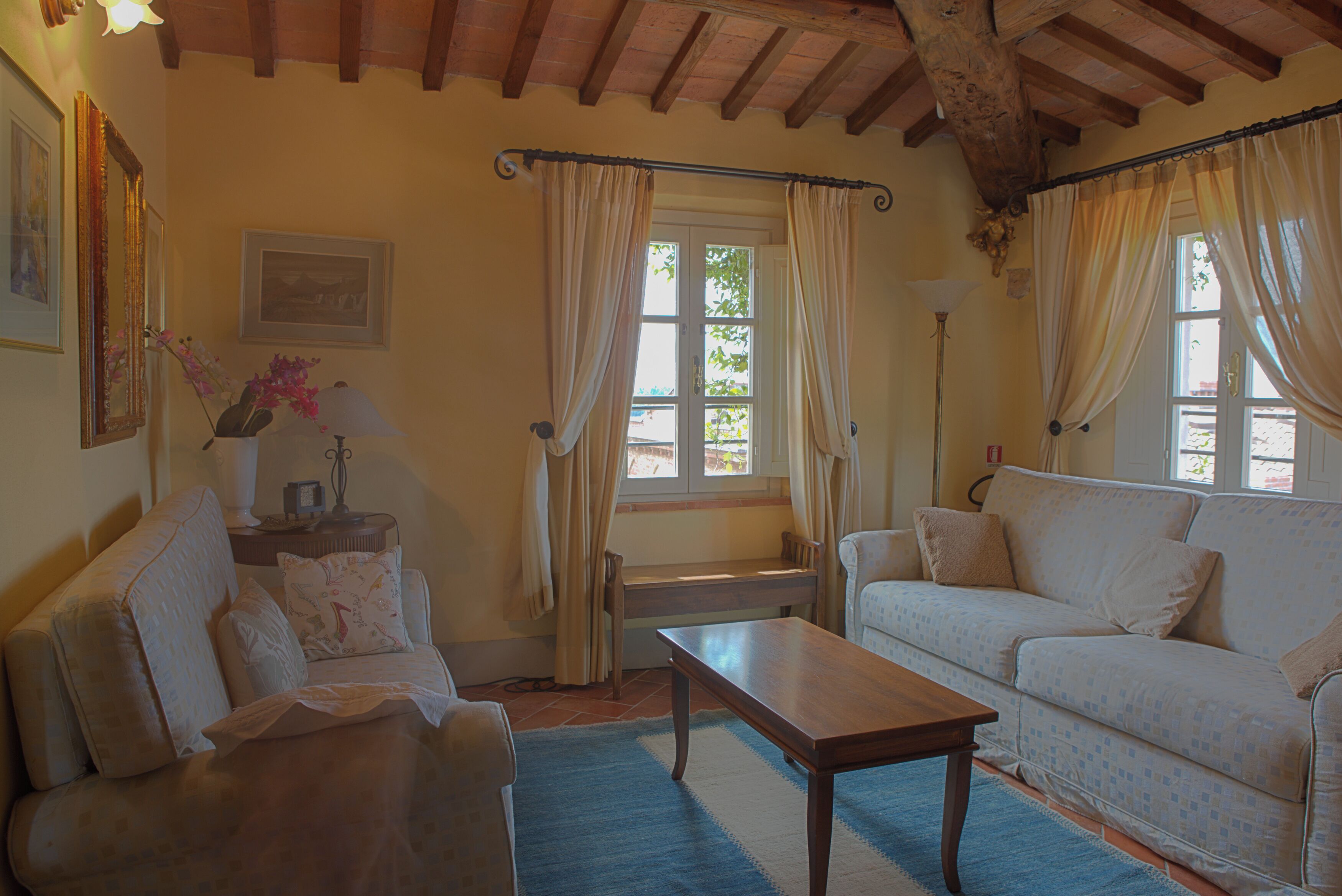 A living room with a sofa, a coffee table, and a window with curtains.