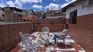 A rooftop patio with a tiled floor, metal chairs, a small table, and a potted plant. - Hotel Mediterráneo Quito (Quito)