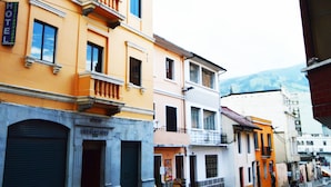 A row of yellow buildings with balconies, a closed shop on the left, and a sign that reads "Hotel Mediterraneo". - Hotel Mediterráneo Quito (Quito)
