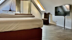 Ein modernes Schlafzimmer mit einem großen Bett, einem Fernseher und einem Oberlicht.