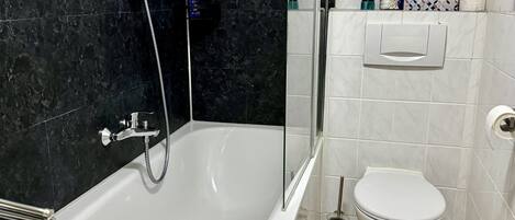 Un baño moderno con bañera, inodoro y zona de ducha.