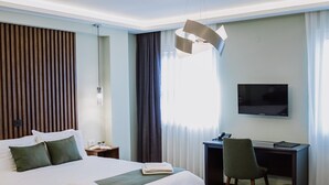 Habitación de hotel con una cama grande, un escritorio, una silla y un televisor.