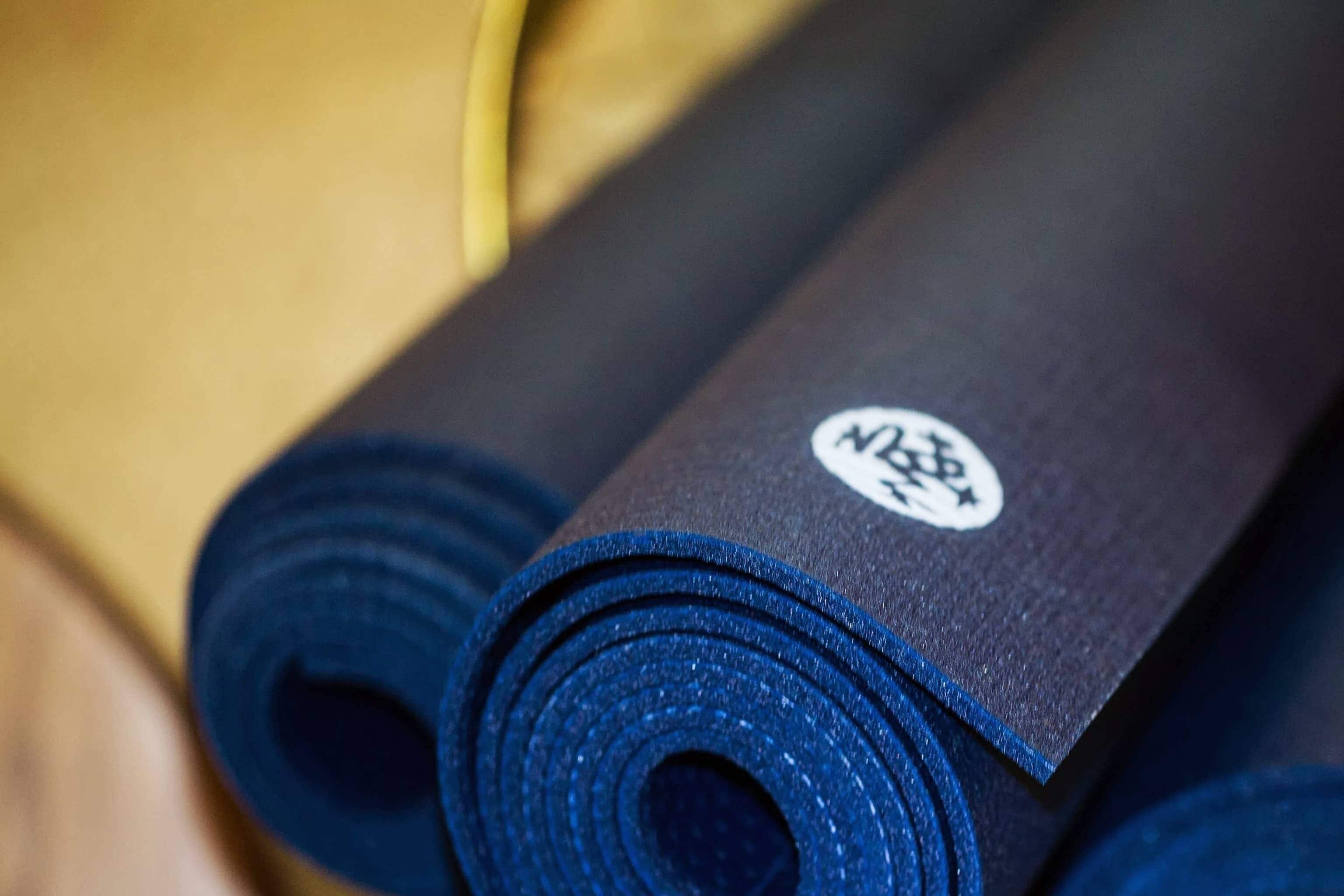 A close-up of a rolled-up yoga mat with a logo on it.